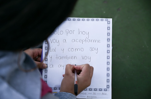 Estudiante escribiendo una nota sobre aceptarse personalmente