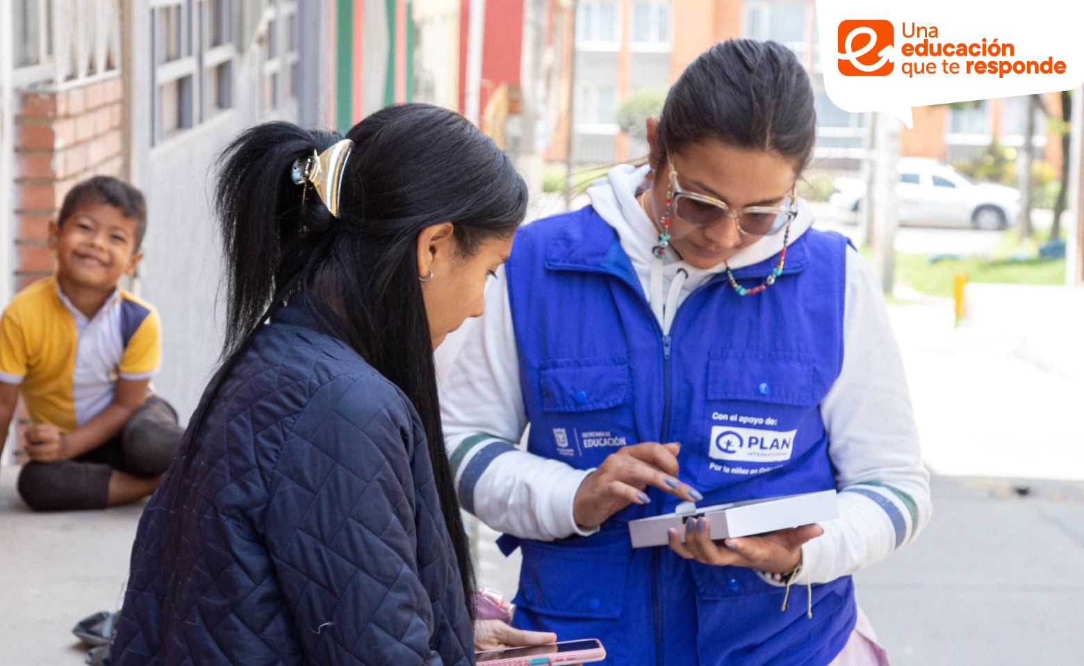 Funcionario de Fundación PLAN con madre de familia