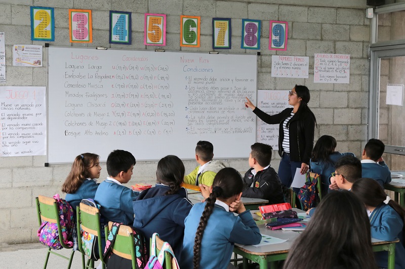 Profe enseñando en el tablero a estudiantes