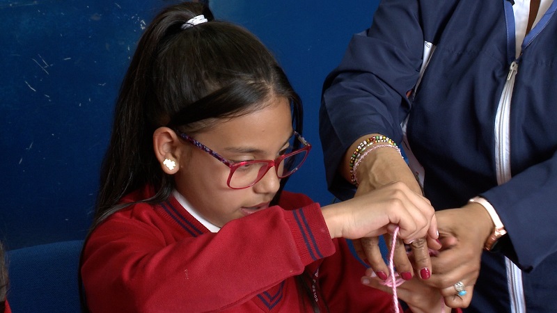 Niña realizando un nudo con un hilo